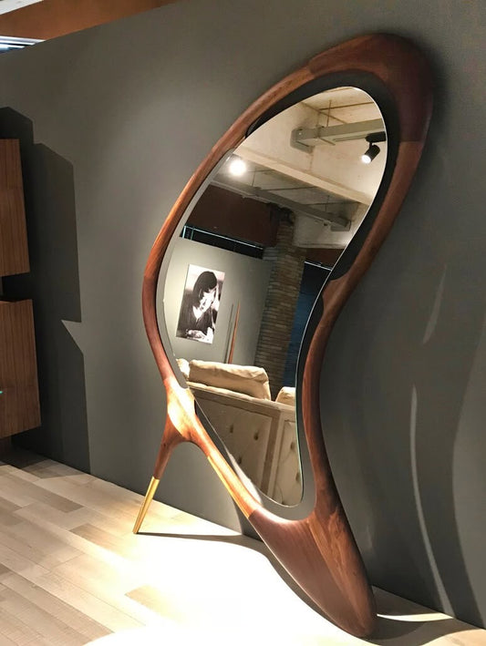 A uniquely designed mirror with an asymmetrical solid American walnut frame and brass leg accents, perfect for contemporary and luxury interiors